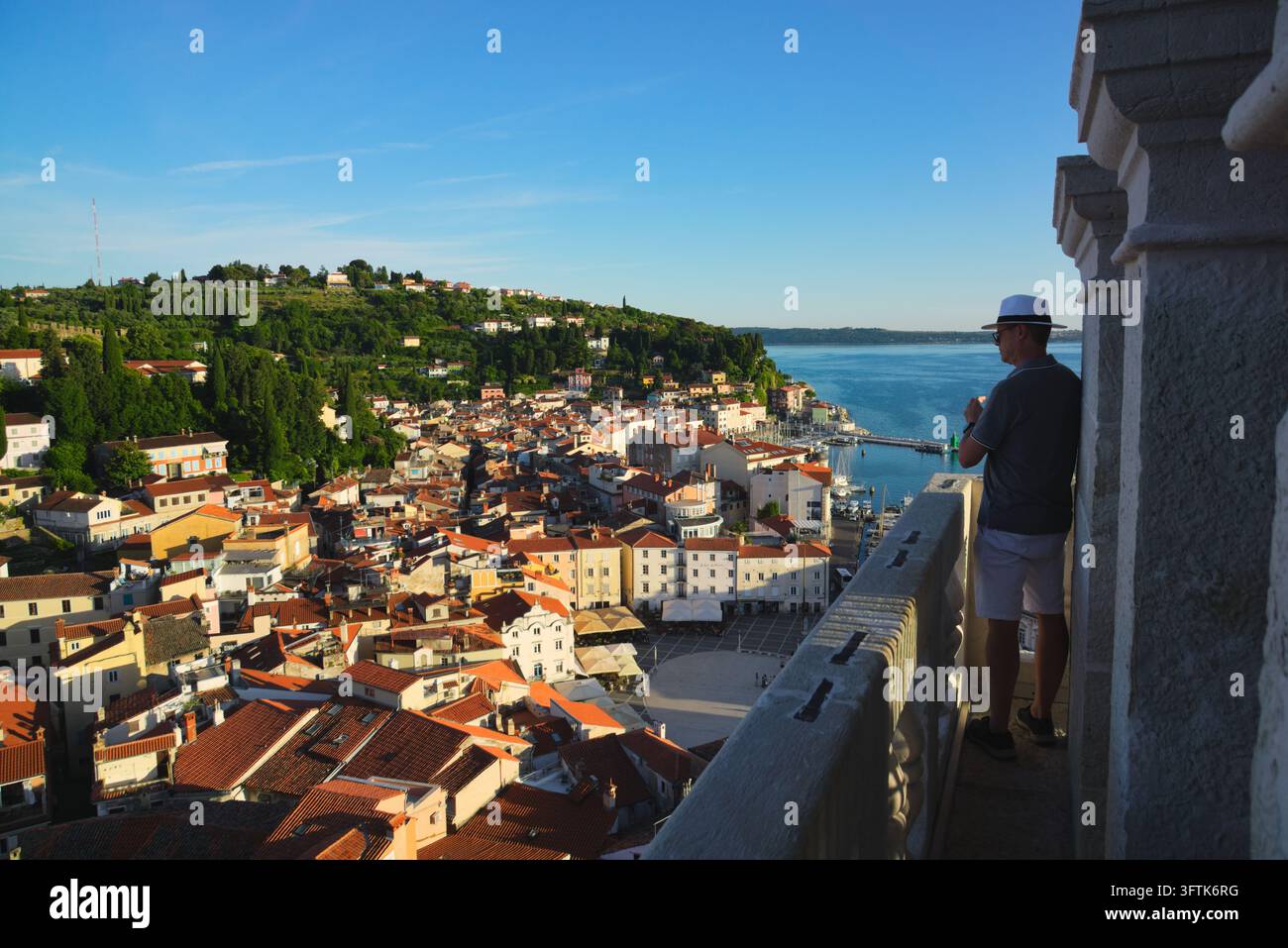 Touriste regardant depuis le clocher de Saint-Georges sur les toits aux tuiles rouges, la place Tartini et le port de Piran, en Slovénie. Banque D'Images