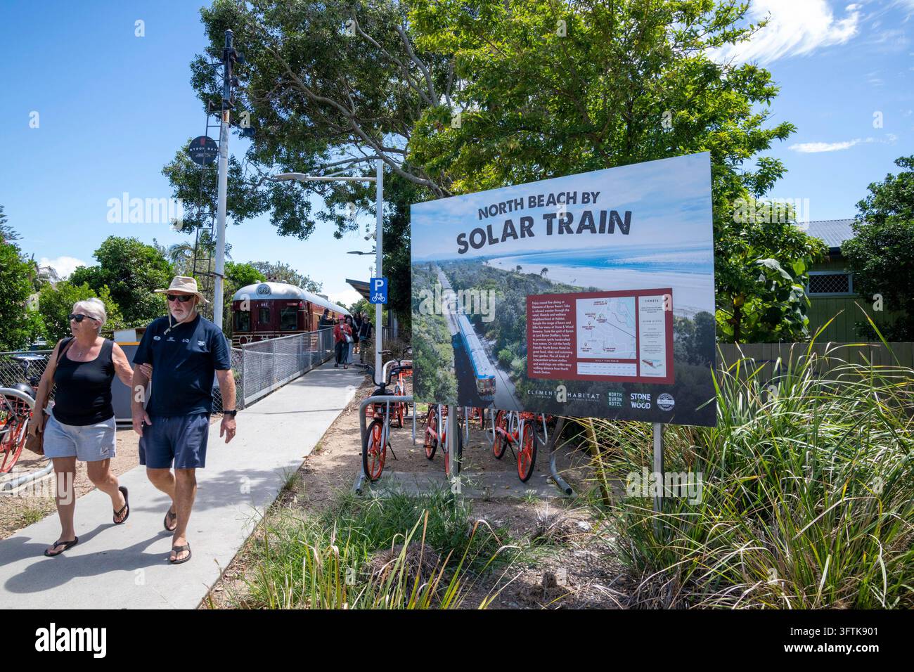 Les passagers marchent à côté d'un panneau d'information sur le train solaire dans une gare de Byron Bay, Northern Rivers, NSW, Australie. Banque D'Images
