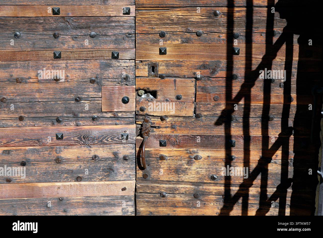 La chapelle baroque de Bionnassay. Un détail de sa porte en bois cloutée, avec l'ombre d'une porte projetée dessus. Saint-Gervais. France. Banque D'Images