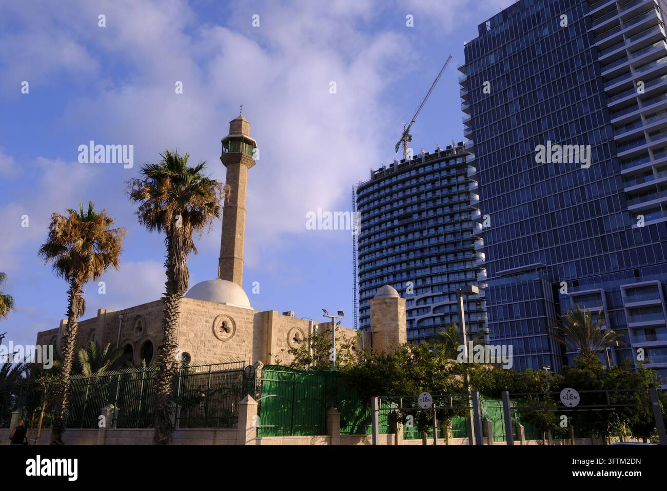 À Tel Aviv, en Israël, une mosquée traditionnelle se dresse à côté de gratte-ciel modernes et hauts sous un ciel nuageux. Banque D'Images