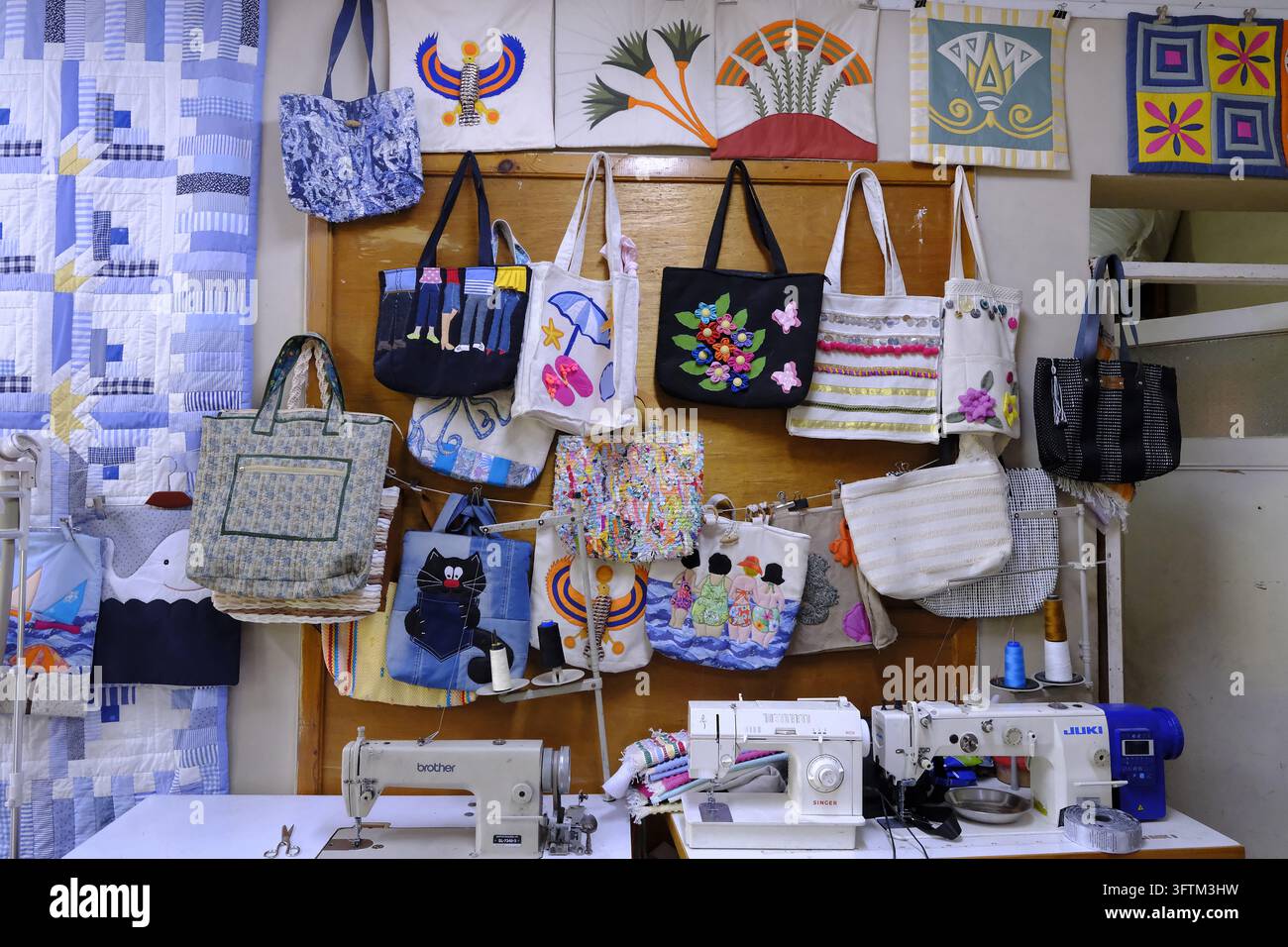 Dans un atelier communautaire à Moqattam, Le Caire, des sacs colorés et faits à la main à partir de matériaux recyclés sont suspendus au-dessus de plusieurs machines à coudre. Banque D'Images