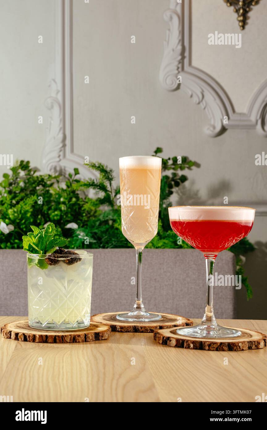 Trois cocktails artisanaux uniques sur des dessous de verre en bois Banque D'Images