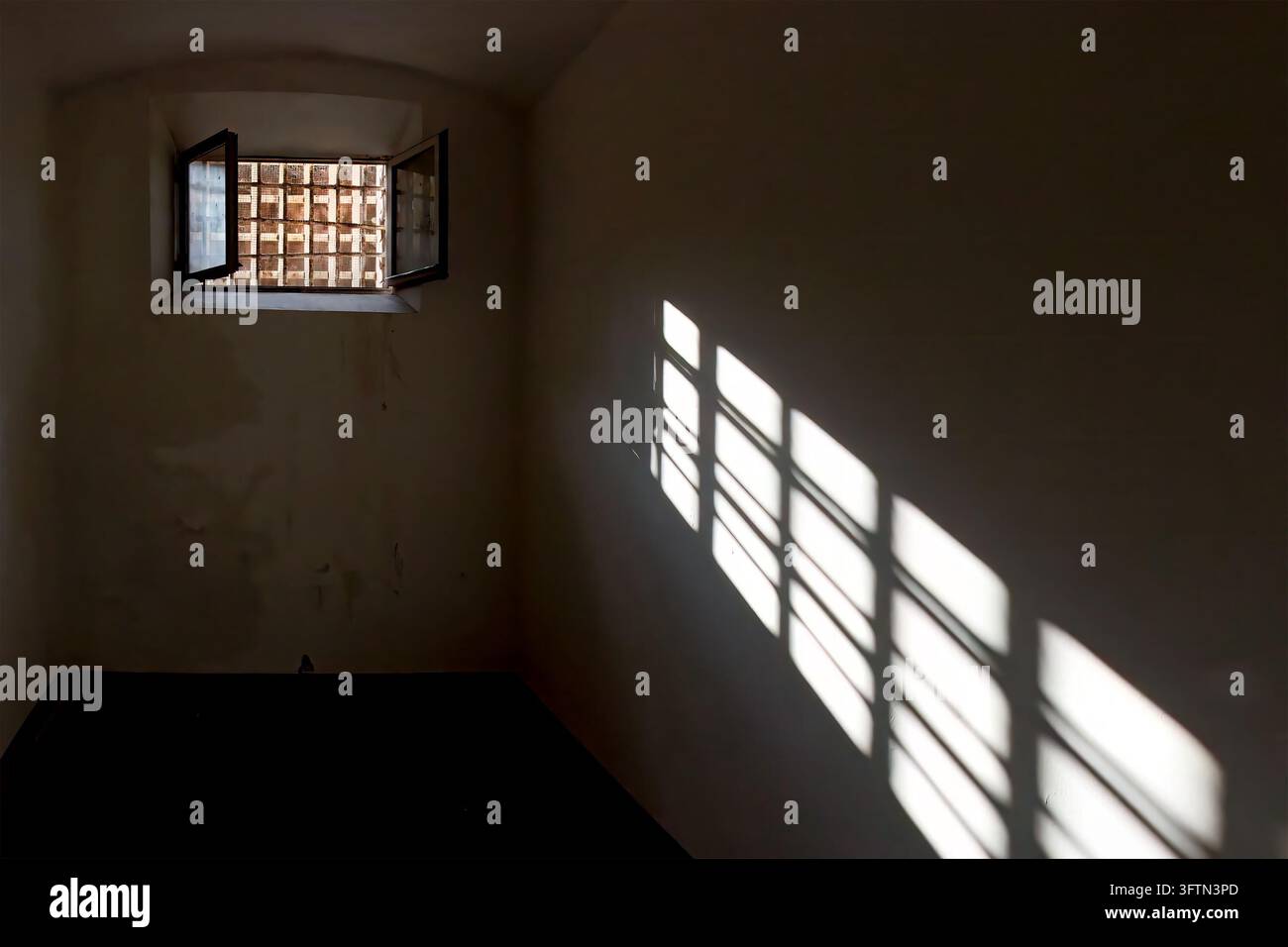 La lumière entre dans la pièce par la fenêtre d'une cellule de prison avec des barreaux projetant une ombre dramatique sur le mur Banque D'Images