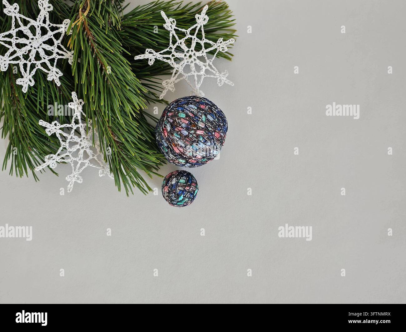 Composition de table de Noël avec des flocons de neige crochetés à la main et des boules décoratives colorées Banque D'Images