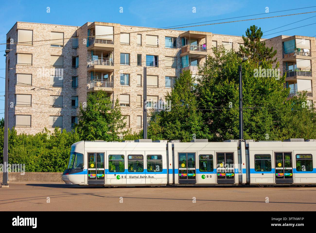 ZURICH, SUISSE - 5 JUILLET 2026 : Tramway moderne VBG Glattalbahn passant devant un immeuble d'appartements résidentiels dans le canton de Zurich Banque D'Images
