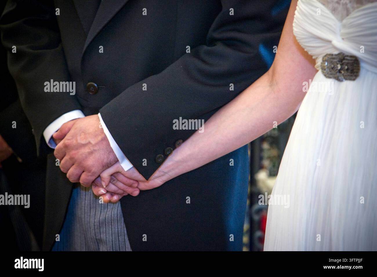 Les mariés se tiennent la main lors de leur cérémonie de mariage solennelle à Séville, Andalousie, Espagne. Un moment symbolique d'union et d'engagement. Banque D'Images