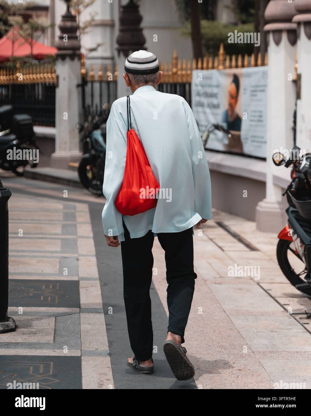 Un homme musulman en robe blanche et calotte marche dans une rue de Kampong Glam, Singapour Banque D'Images