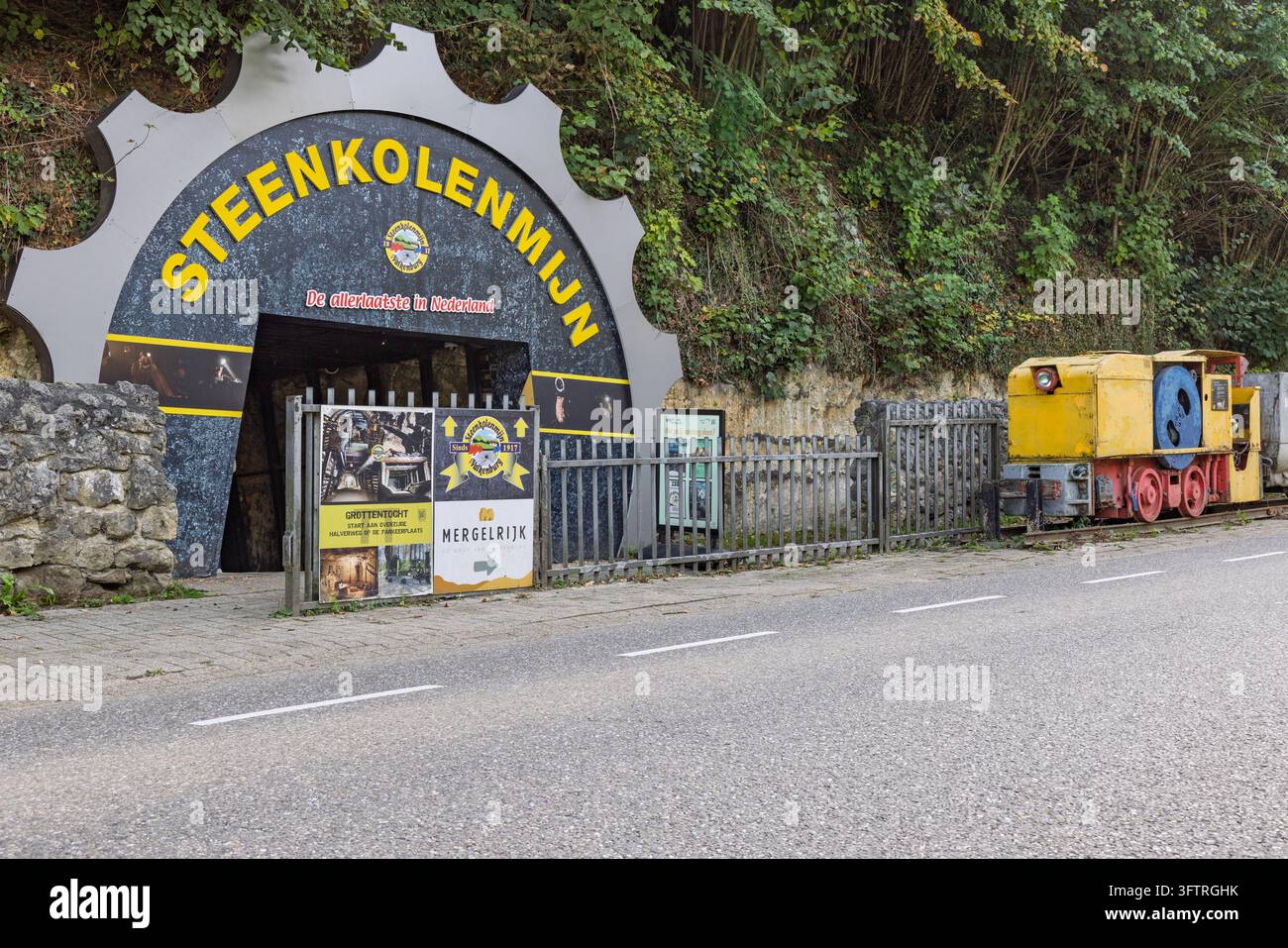 Valkenburg, Pays-Bas – 04 octobre 2026 : Portail d’entrée du musée de la mine de charbon Steenkolenmijn en forme de roue dentée avec une locomotive historique jaune de l’industrie minière Banque D'Images