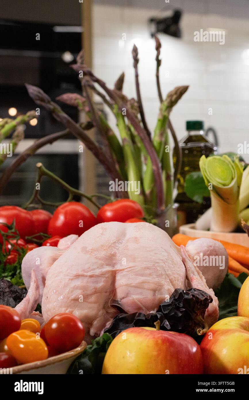 Poulet entier cru entouré de légumes frais Banque D'Images