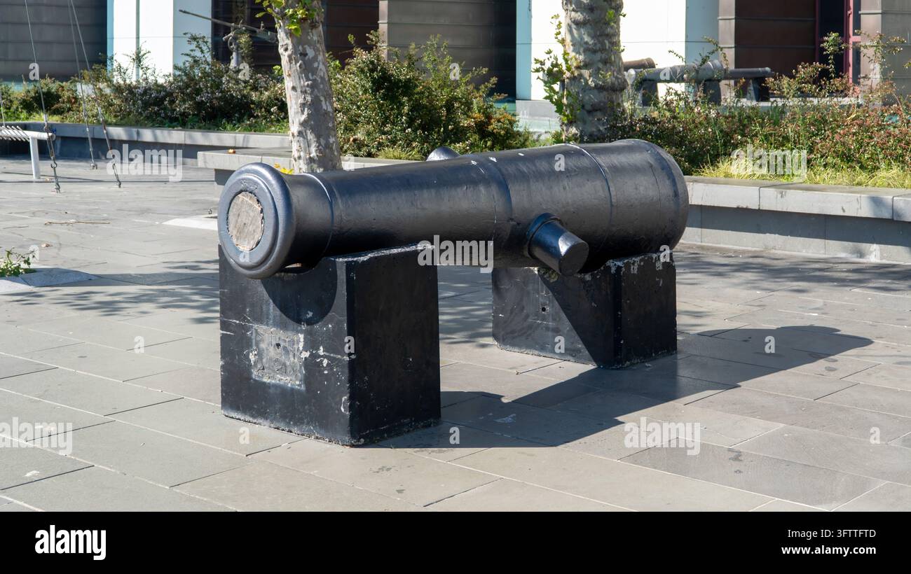 Canon noir de l'ère ottomane sur des supports en pierre au musée naval d'Istanbul à Besiktas, Turquie, exposé en plein air sur une place pavée parmi des arbres Banque D'Images