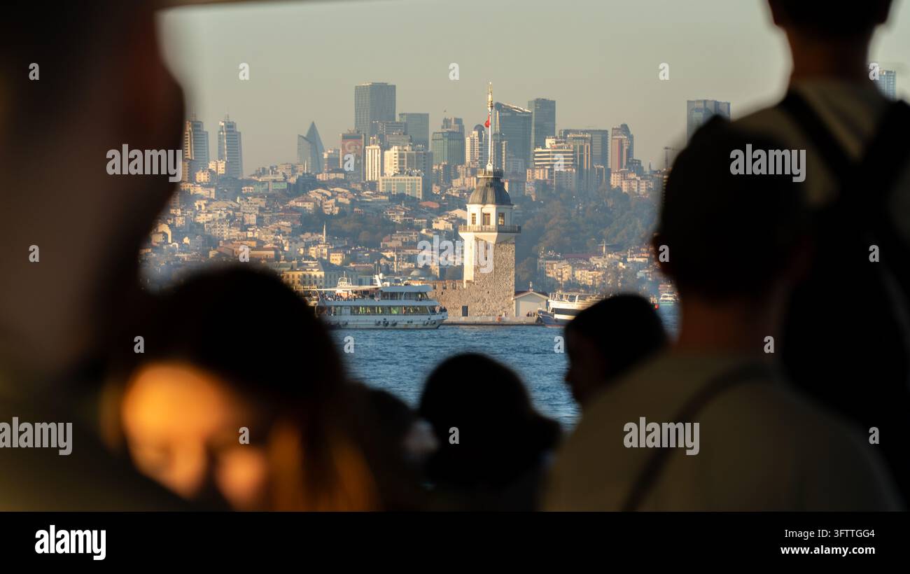 Istanbul, Turquie - 10 octobre 2026 : la Tour de la Vierge sur son petit îlot au large d'Uskudar, un symbole médiéval d'Istanbul, vu à travers les silhouettes de ferries Banque D'Images