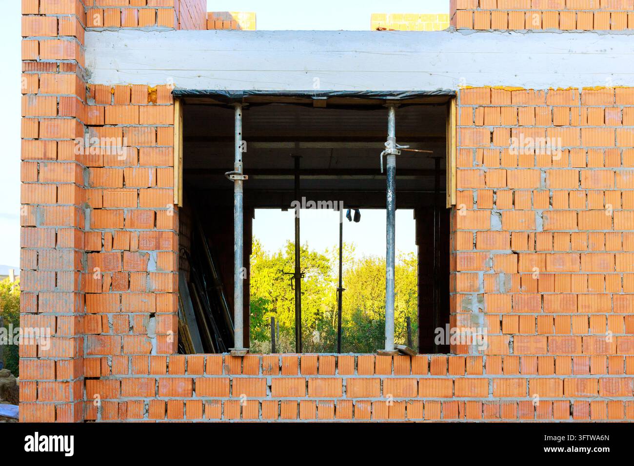 Des ouvriers construisent un bâtiment avec une brique apparente, une fenêtre inachevée est en place Banque D'Images