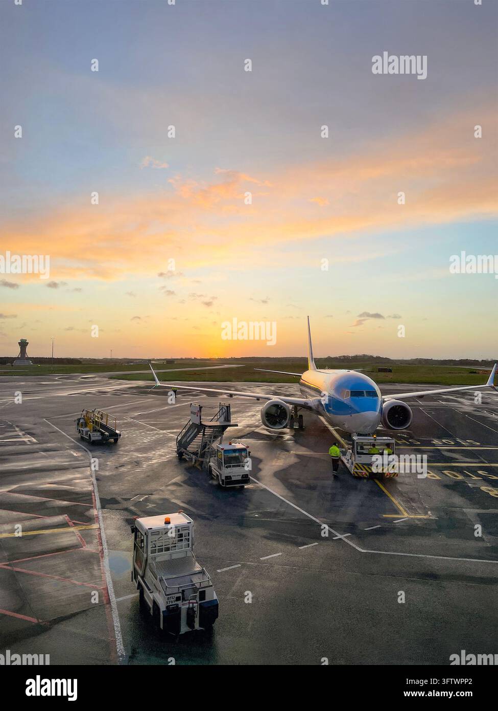 Avion bleu TUI Boeing 737 sur le tarmac avec des véhicules de service et du personnel au coucher du soleil Banque D'Images