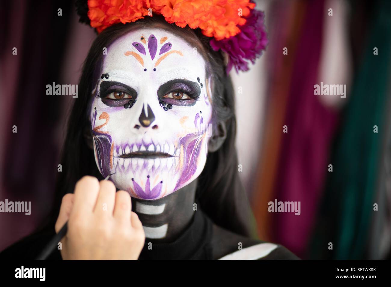 Gros plan d'un maquilleur appliquant les détails finaux sur le maquillage de crâne Catrina. Banque D'Images