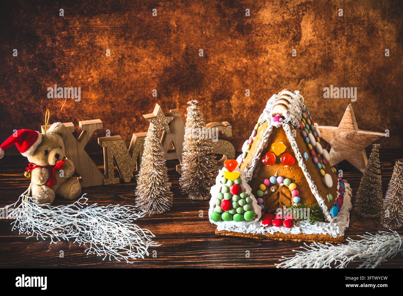Maison en pain d'épices décorée de bonbons colorés et décoration de noël sur fond de bois. Banque D'Images
