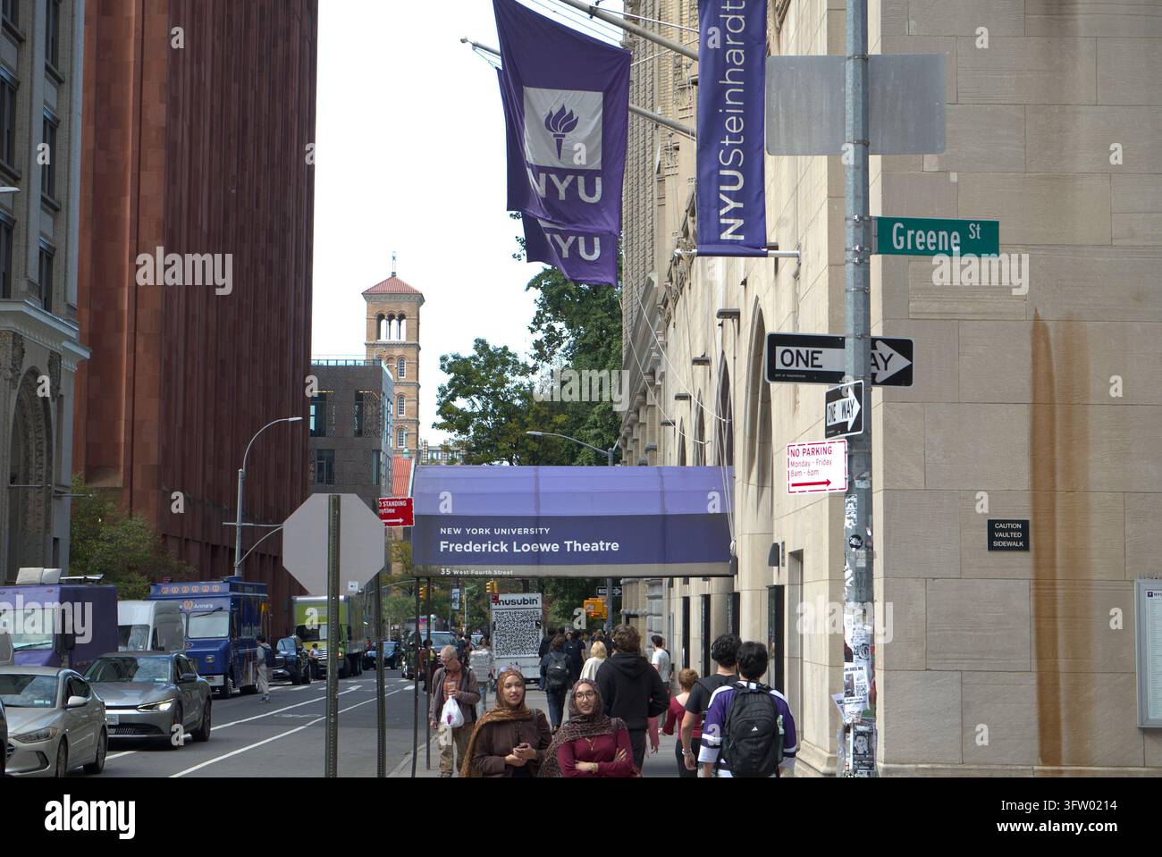 New York, États-Unis. Étudiants près de la signalisation de l'Université de New York (NYU) et d'un drapeau universitaire dans le West Village de Manhattan, mettant en avant la vie sur le campus Banque D'Images