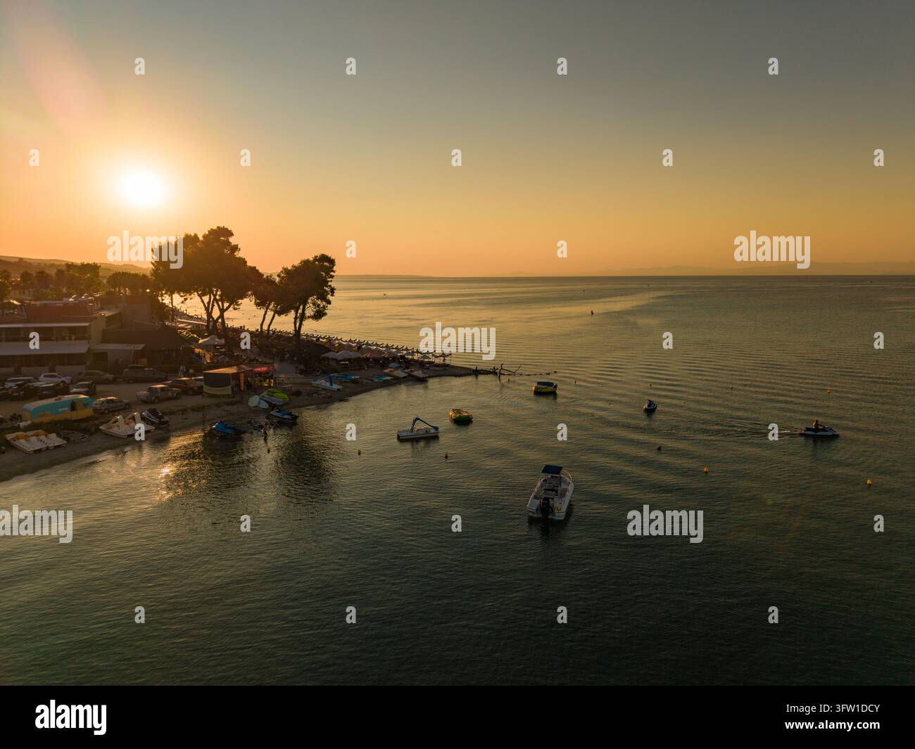 Sports nautiques près des pins au coucher du soleil, Pefkochori, Chalcidique, Grèce Banque D'Images