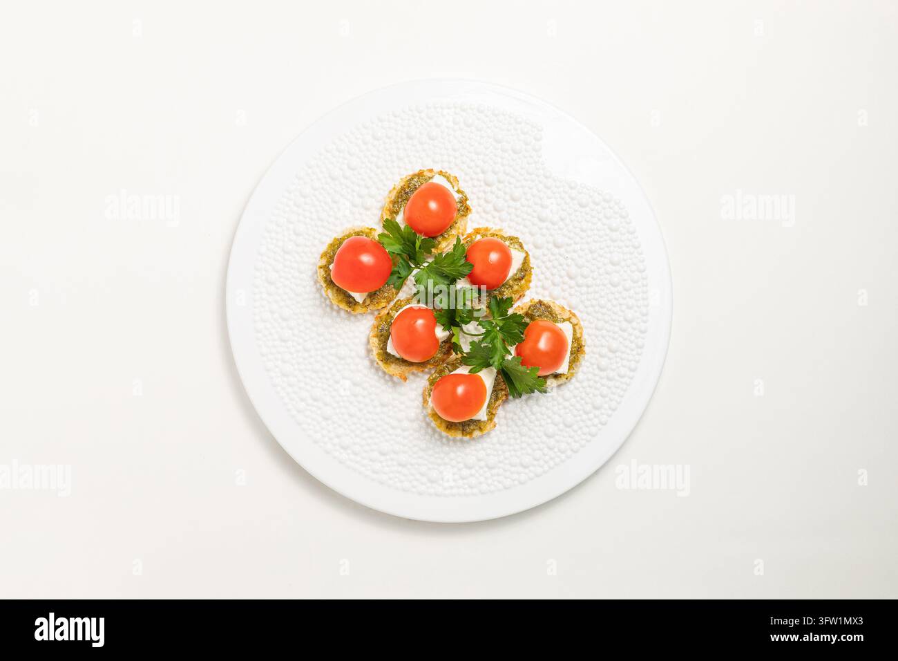 Albanie, Fier 2026 01 19 : Plan par-dessus de canapés gourmands avec des tomates cerises, du fromage et du pesto sur une assiette blanche. Banque D'Images