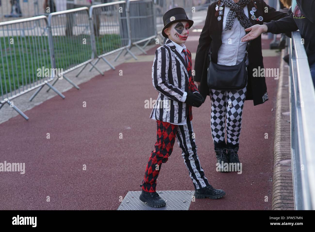 Enfant en costume rayé noir et blanc avec maquillage du visage debout à côté d'un adulte pendant la procession HBBS à Hastings, en Angleterre. Banque D'Images