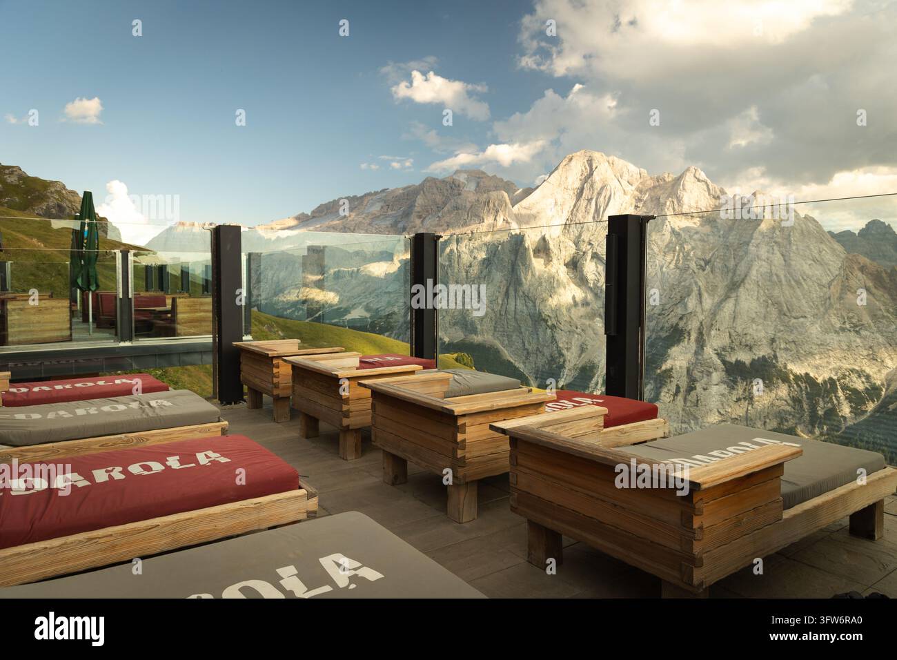 Terrasse de détente extérieure avec transats en bois surplombant des sommets montagneux dramatiques dans les Dolomites, Alpes italiennes, par une journée d'été ensoleillée. Banque D'Images
