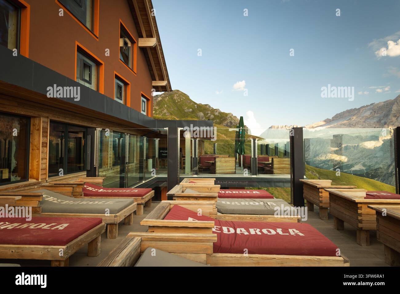 Terrasse de détente extérieure avec transats en bois surplombant des sommets montagneux dramatiques dans les Dolomites, Alpes italiennes, par une journée d'été ensoleillée. Banque D'Images