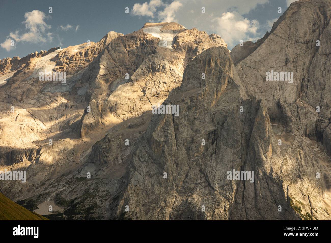 Vue dramatique du massif montagneux du Marmolada et de son glacier dans les Dolomites italiennes. Une lumière chaude du soleil illumine les falaises de calcaire abruptes Banque D'Images