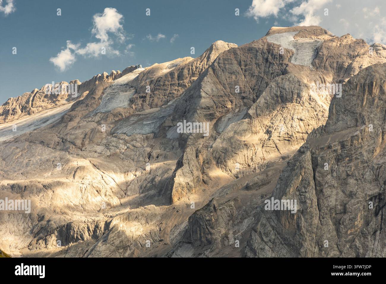 Vue dramatique du massif montagneux du Marmolada et de son glacier dans les Dolomites italiennes. Une lumière chaude du soleil illumine les falaises de calcaire abruptes Banque D'Images