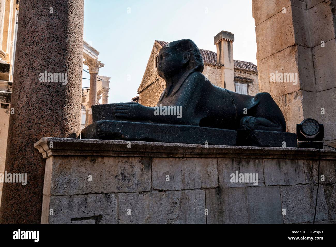 Sphinx en granit noir de l'Égypte antique exposée à côté des colonnes romaines du Palais de Dioclétien à Split, Croatie. Sculpture et architecture historiques Banque D'Images