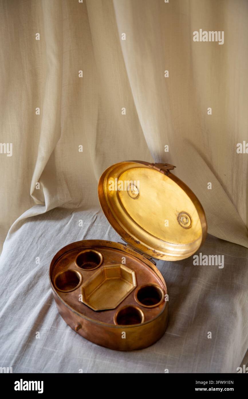 Vue en hauteur d'une boîte Paan vintage en laiton ouverte (Paandaan) révélant les compartiments internes sur une surface en lin. Banque D'Images