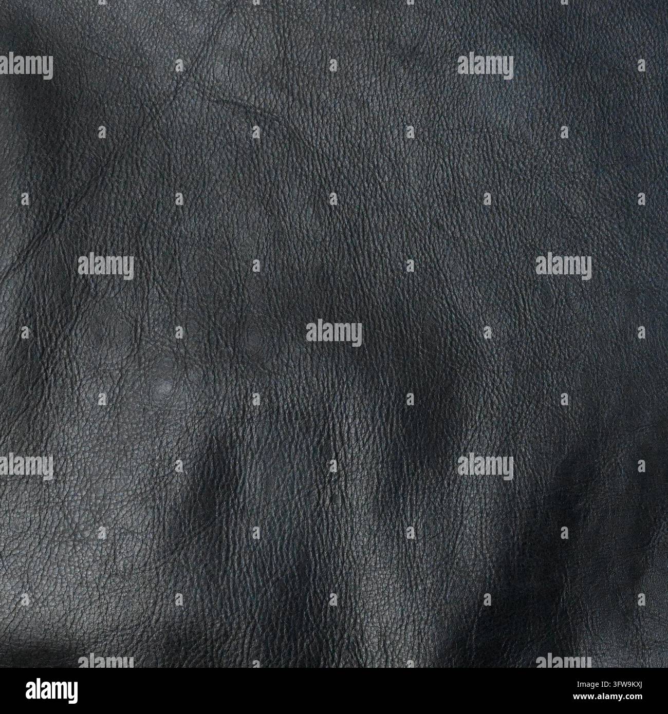 Vue large d'une surface en cuir noir avec des motifs de grain naturels abstraits, une texture rugueuse et irrégulière, et des reflets et ombres subtils Banque D'Images