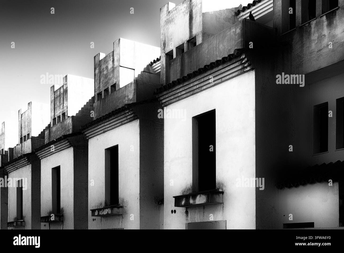 Une rangée de maisons de ville simples avec de hautes façades et des ouvertures de fenêtres sombres en noir et blanc contrastés, Manilva, province de Malaga, Andalousie, Costa del Banque D'Images