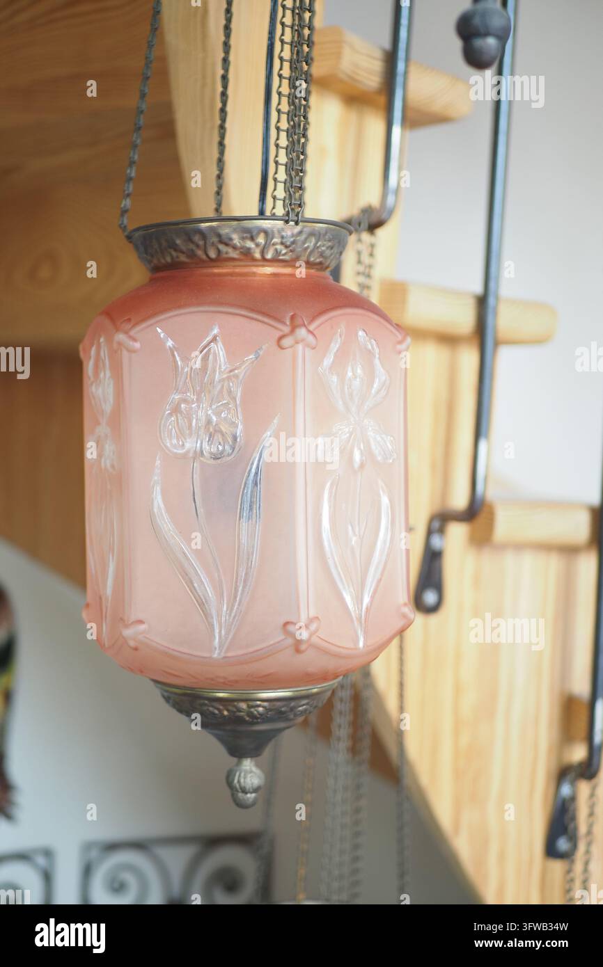 Plafonnier en verre rose suspendu avec chaînes métalliques dans un intérieur en bois Banque D'Images