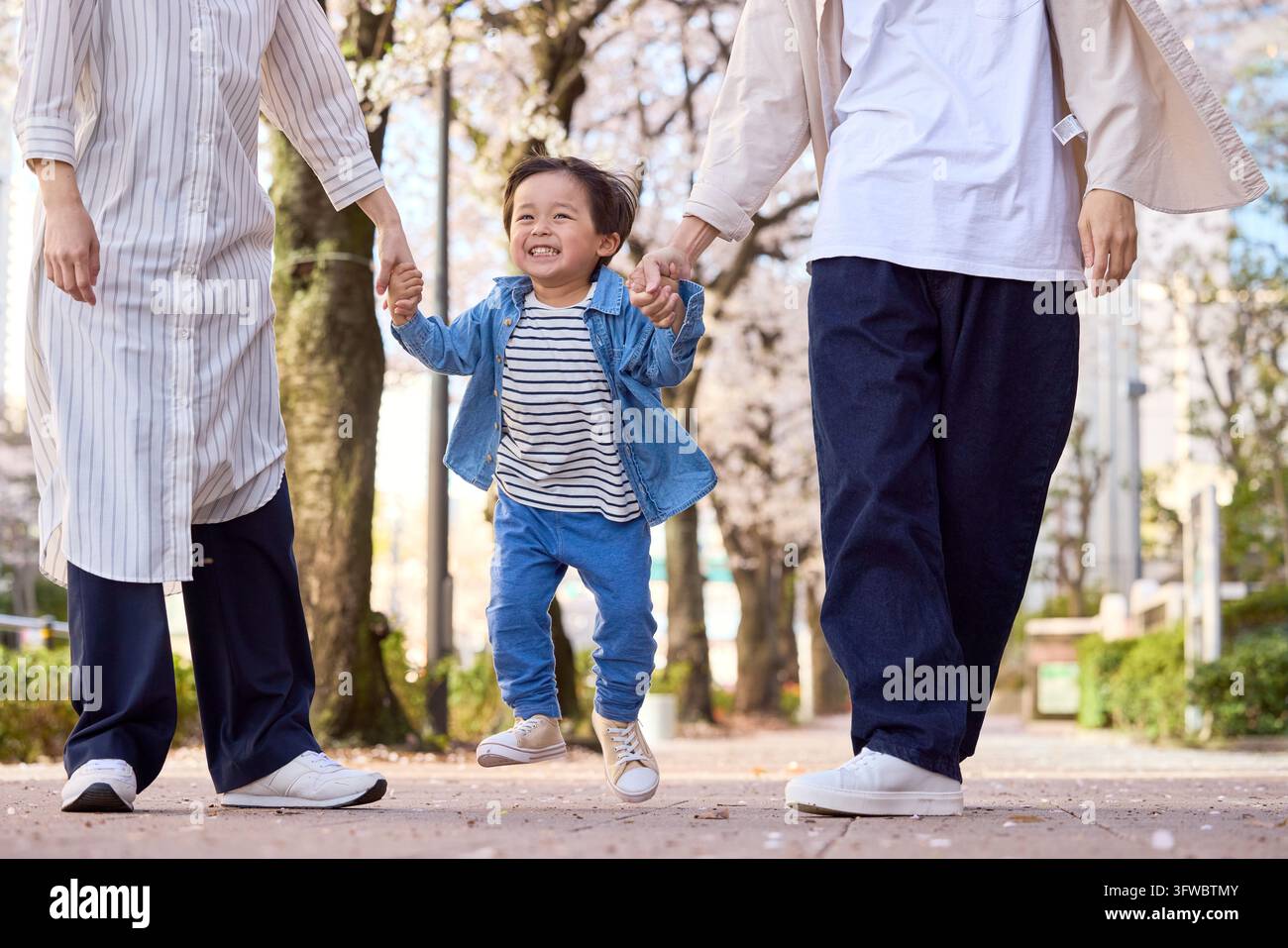 Parent et enfant japonais marchant main dans la main avec le sourire aux lèvres Banque D'Images