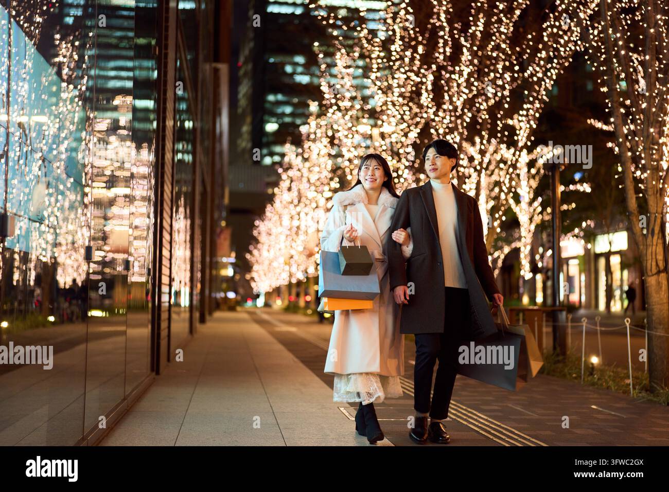 Couple japonais profitant des lumières de Noël dans la ville la nuit Banque D'Images
