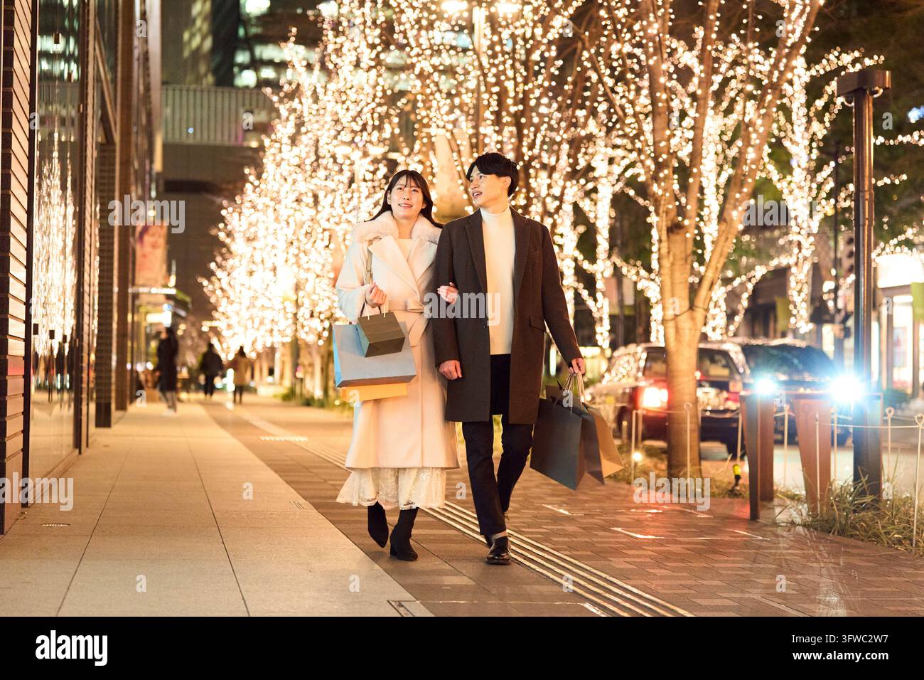 Couple japonais marchant dans la ville la nuit, illuminé par les lumières Banque D'Images