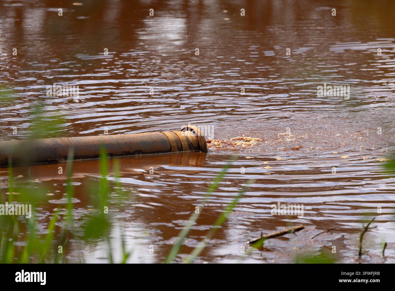 Eau sale s'écoulant d'un tuyau d'égout dans un réservoir extérieur au Royaume-Uni. Banque D'Images
