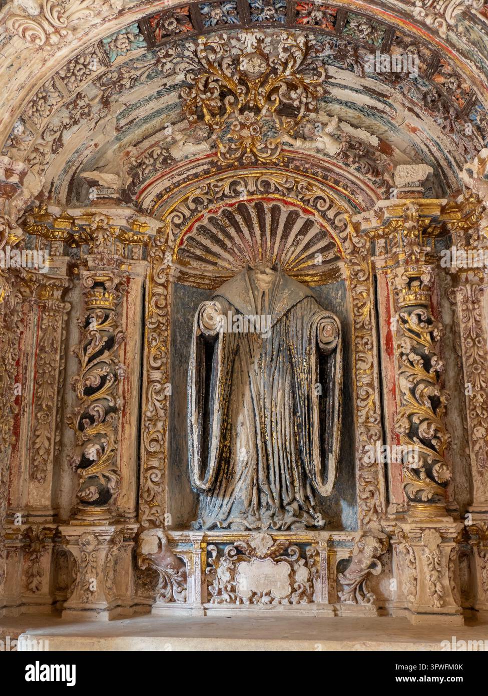 Ancienne statue sans tête dans une niche ornée – Une statue sans tête érodée d'une figure en robes se dresse dans une arche baroque finement sculptée et dorée Banque D'Images