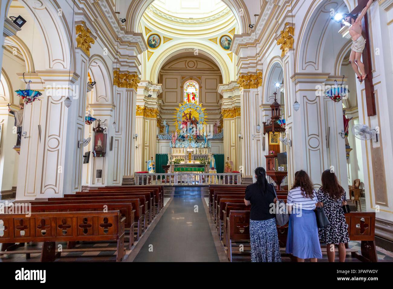 Trois femmes descendant l'allée d'une église catholique blanche, Province occidentale, Negombo, Sri Lanka Banque D'Images