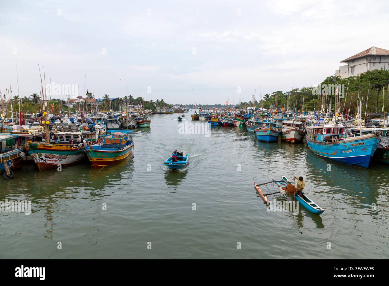 Bateaux de pêche amarrés le long d'un canal portuaire avec de petits bateaux qui passent, Province occidentale, Negombo, Sri Lanka Banque D'Images