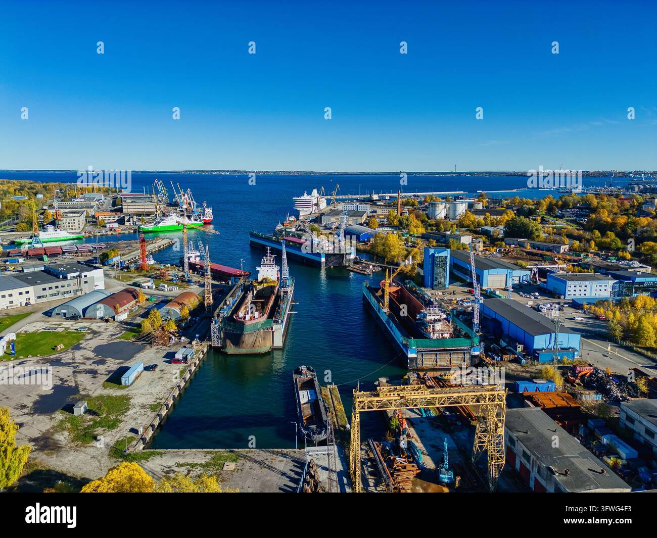 Vue par drone d'un chantier naval industriel avec des docks secs flottants et des navires de charge par une journée ensoleillée Banque D'Images