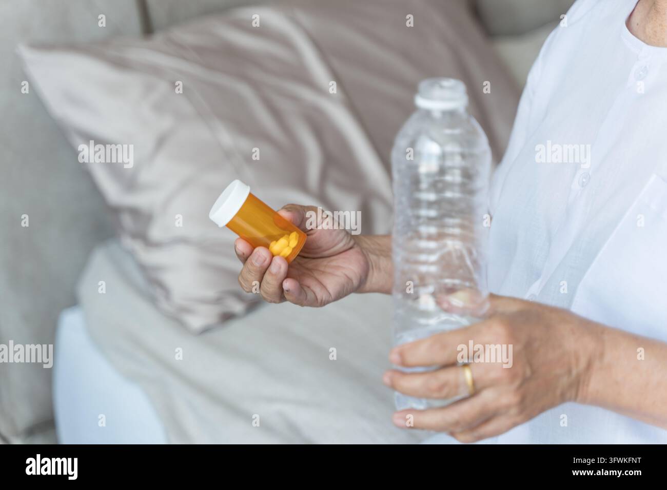 Sénior tenant une bouteille de pilules et de l'eau à la maison, se concentrant sur les médicaments pour la gestion de la santé. Idéal pour les soins de santé, le vieillissement, le bien-être et les personnes âgées Banque D'Images