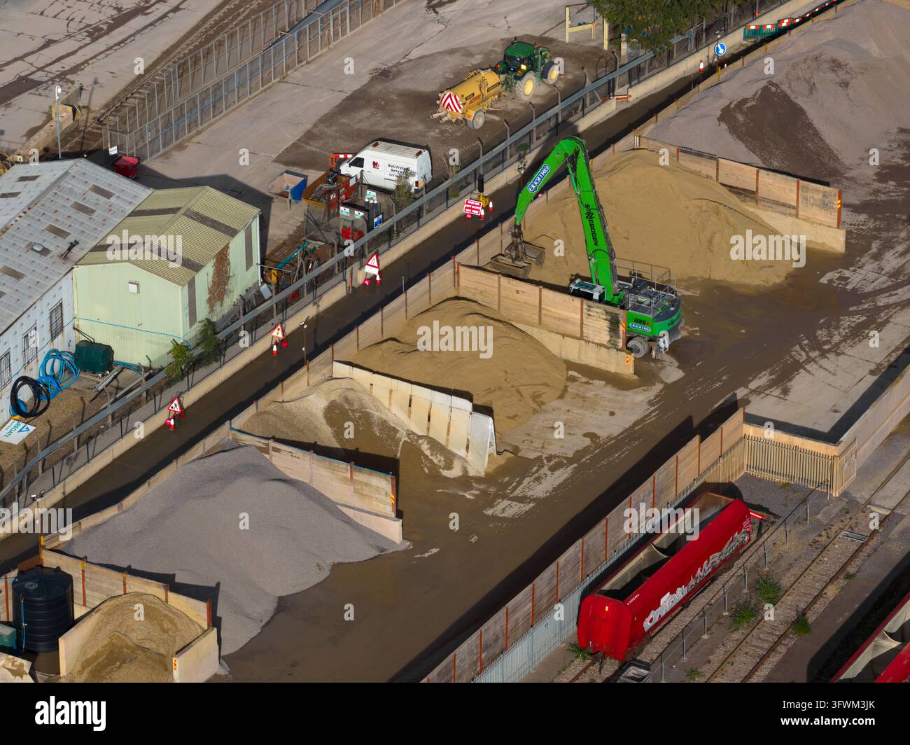 Londres, Angleterre, Royaume-Uni - 08 octobre 2026 : Vue aérienne de l'usine Hanson Ready-mixed Concrete montrant une pelleteuse verte déplaçant du sable et Banque D'Images
