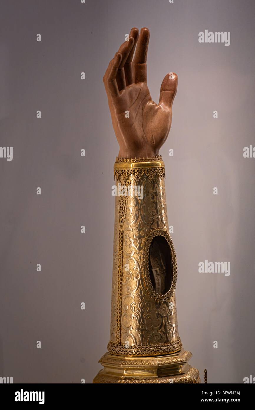 Un gros plan d'un reliquaire religieux ancien en forme de main humaine, enfermé dans un fourreau d'or finement travaillé. L'artefact présente des détails fins Banque D'Images