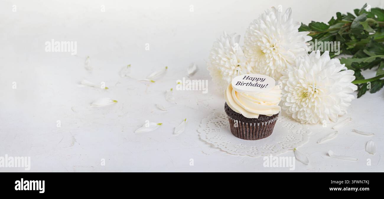 Cupcake décoré avec l'inscription Joyeux anniversaire! avec un bouquet de pivoines. Concept de voeux de vacances, bannière, arrière-plan. Nature morte festive wi Banque D'Images
