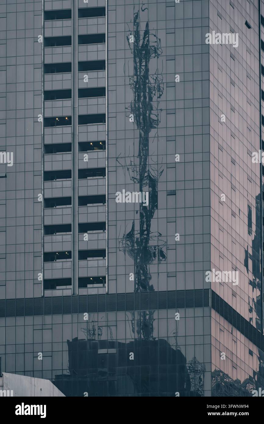 Manila, Philippines, 23 septembre 2026. Une façade en verre et métal d’un bâtiment reflète des structures voisines sous des formes déformées à travers ses panneaux géométriques. Banque D'Images