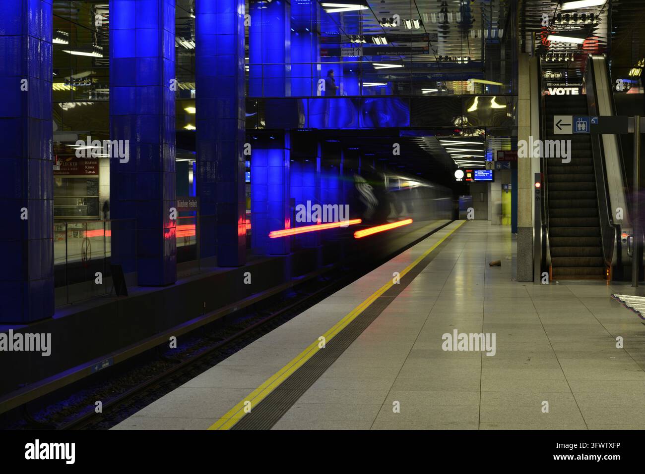 Traînées de lumière d'un train qui passe dans la station de métro bleulement illuminée, métro, Munich Freiheit, Munich, Bavière, Allemagne Banque D'Images