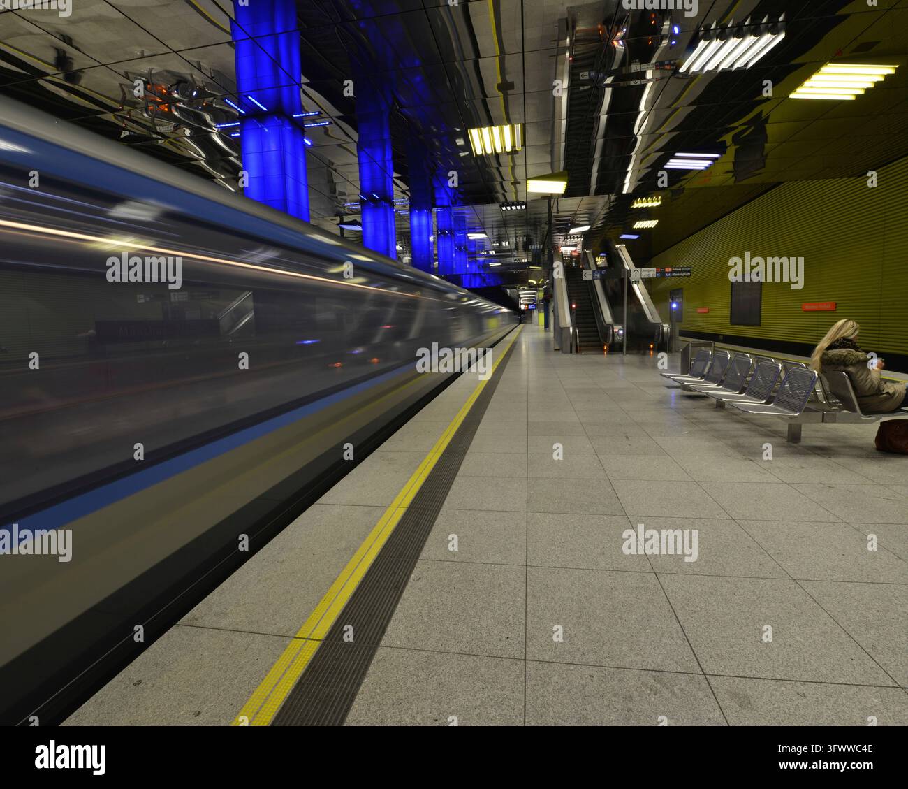 Un train qui passe se brouille dans la station de métro moderne tandis que des colonnes bleues illuminent le quai, le métro, Munich Freedom, Munich, Bavière, Allemagne Banque D'Images