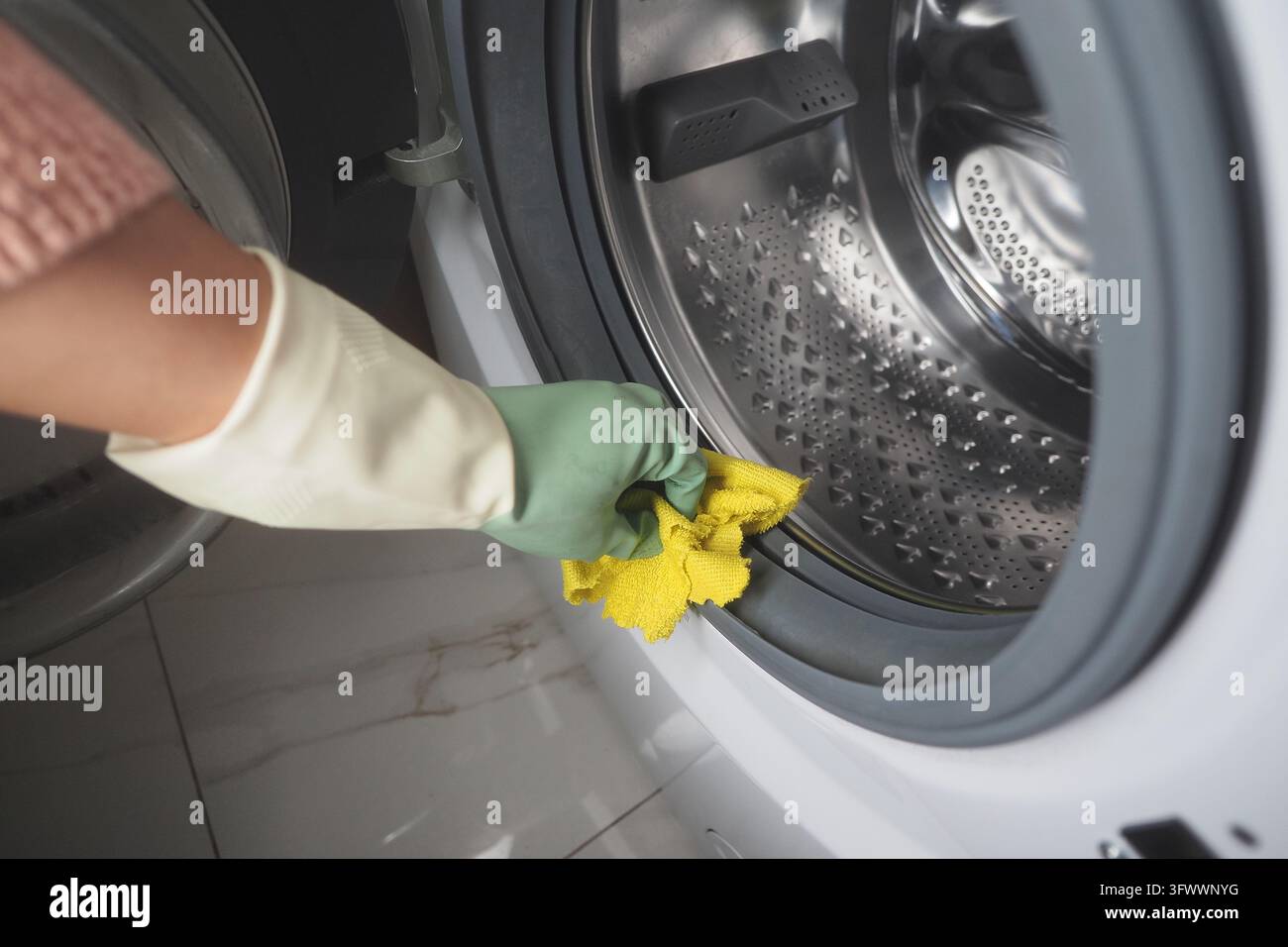 Person nettoyant le joint de porte d'une machine à laver à chargement frontal Banque D'Images