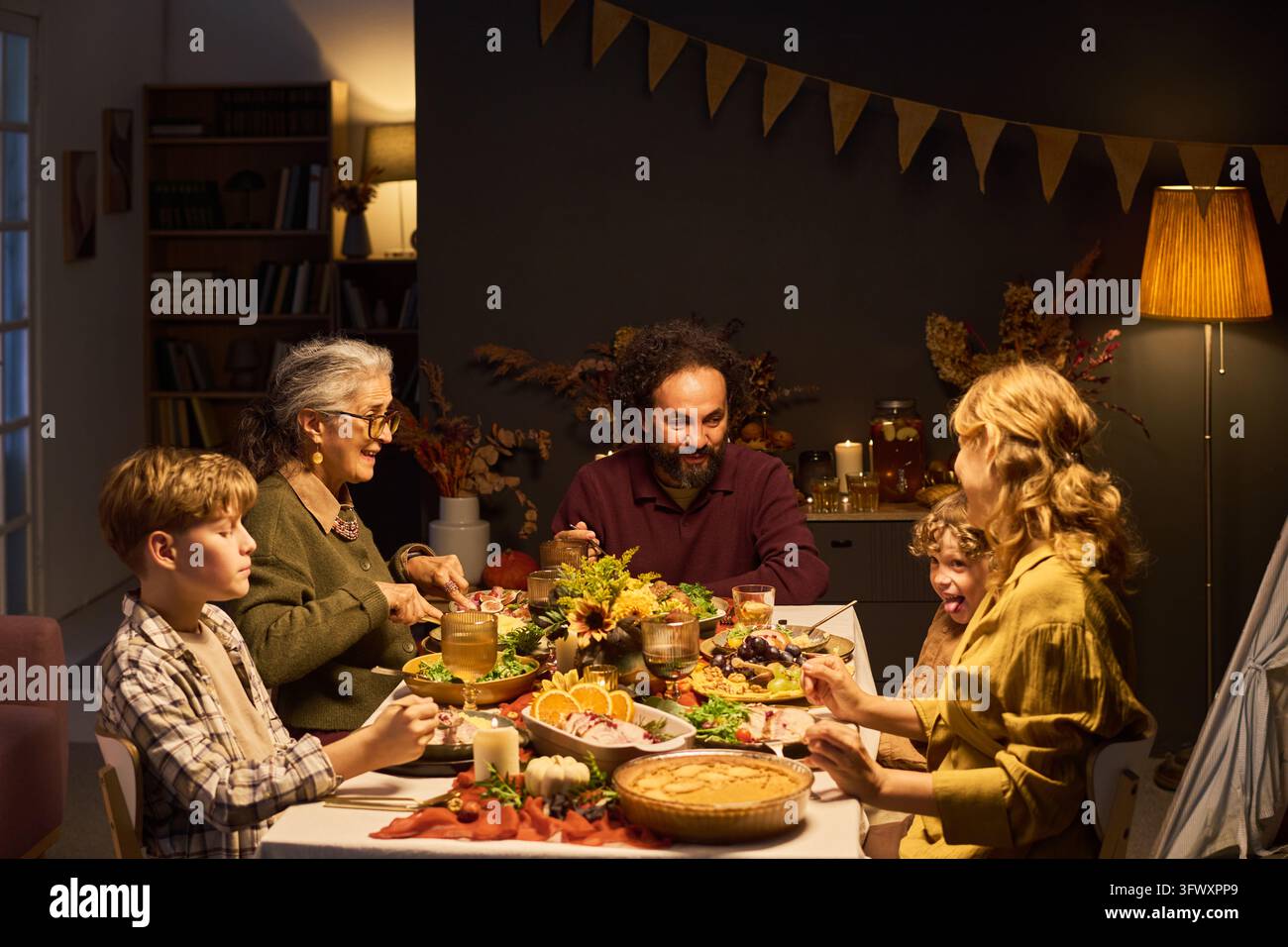 Famille multigénérationnelle dégustant un festin d'automne à une table festive Banque D'Images