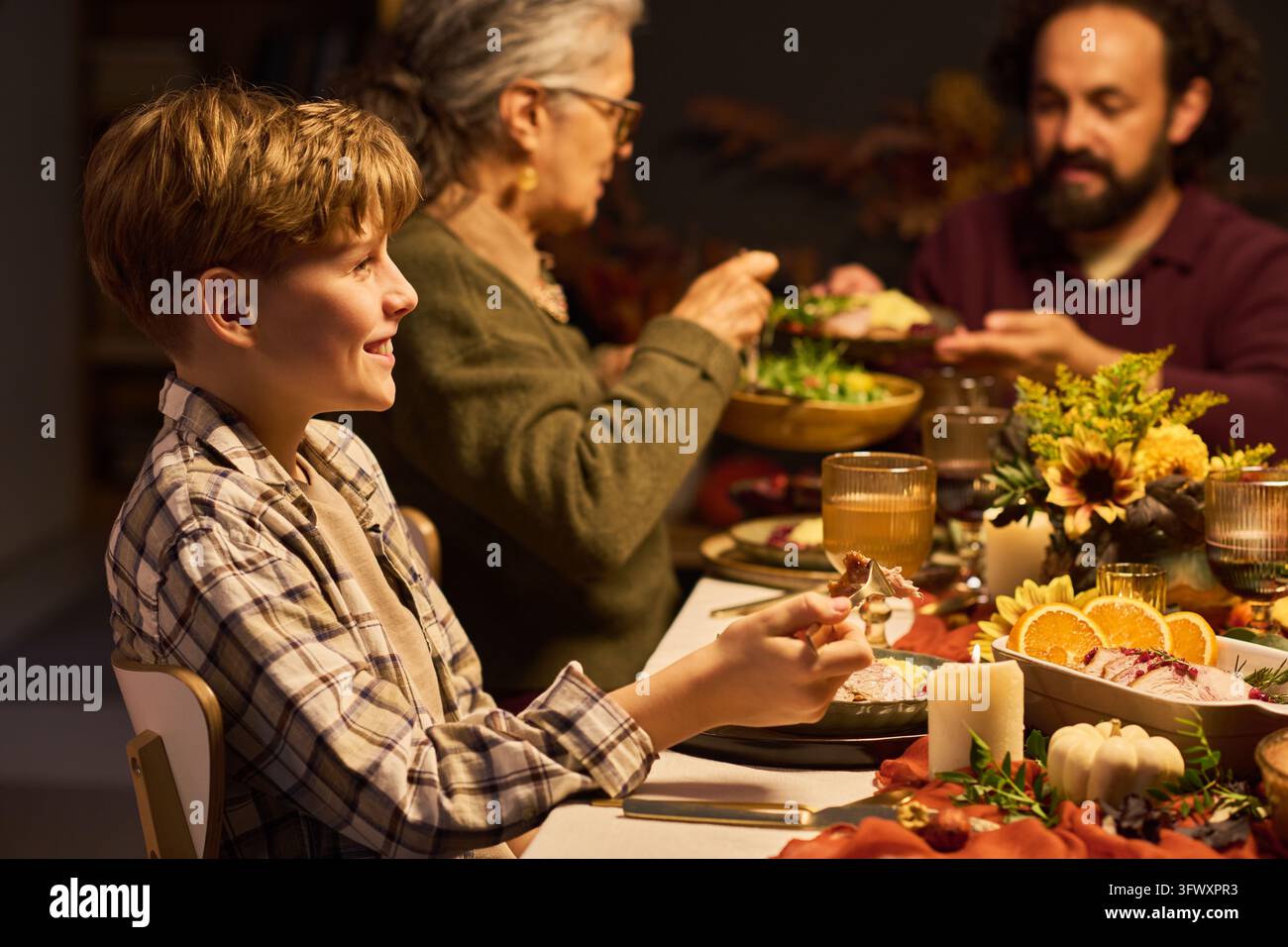 Garçon heureux mangeant un dîner festif de Thanksgiving en famille Banque D'Images